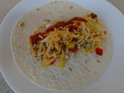 flour tortilla with rice, chicken, and shredded cheese on top