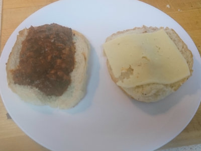 Open hamburger bun with sloppy joes topped with a cheese slice