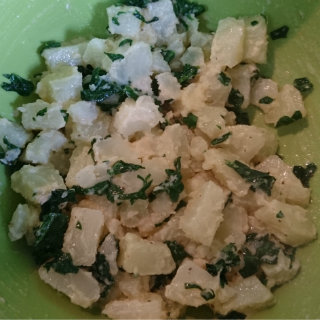 Potato salad with chopped spinach in a green bowl
