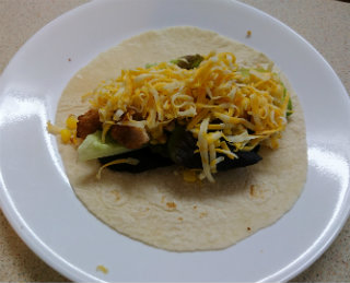 Flour tortilla with diced chicken nuggets, salad greens, and shredded cheese